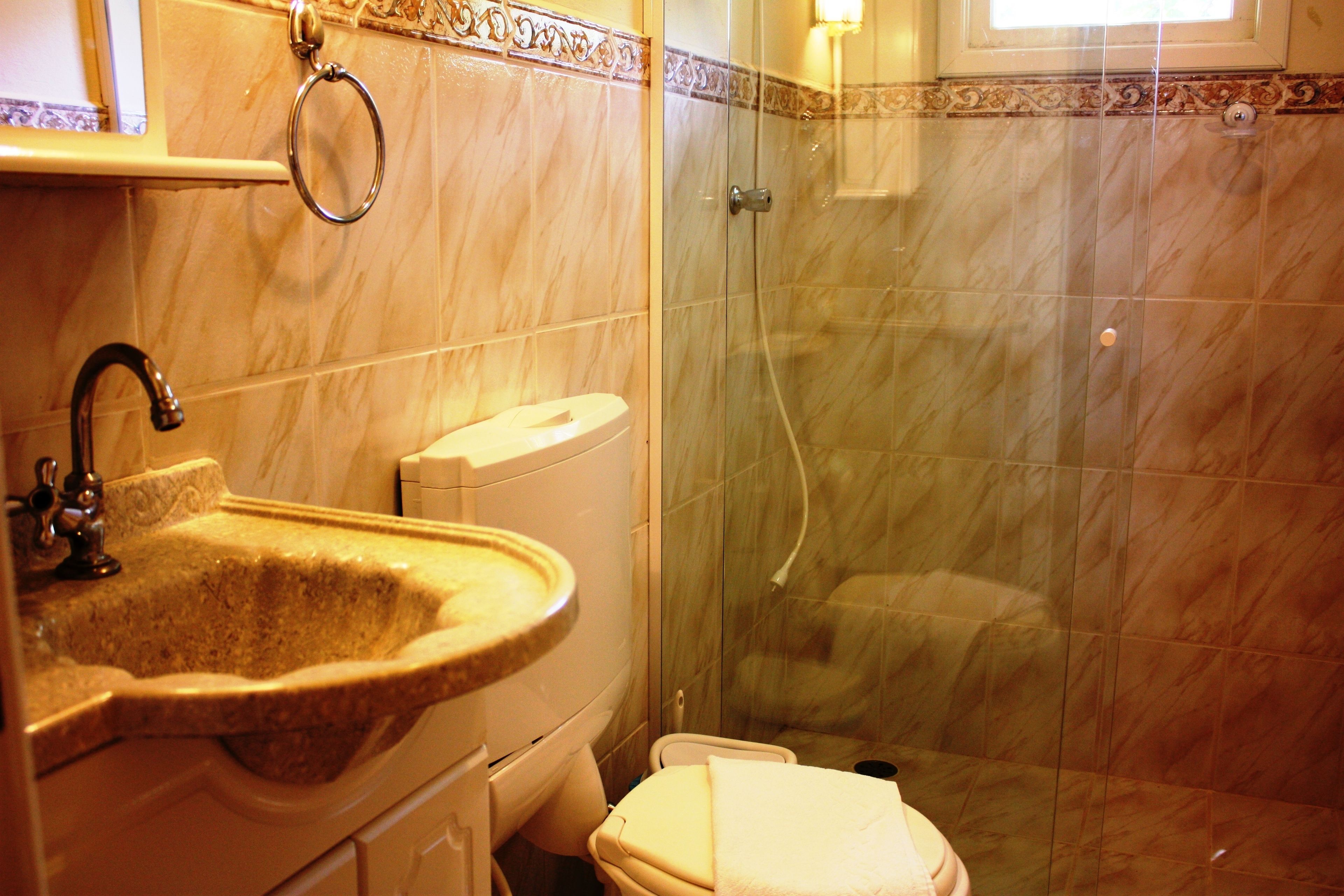 A bathroom with a marble sink, toilet, and a glass-enclosed shower.