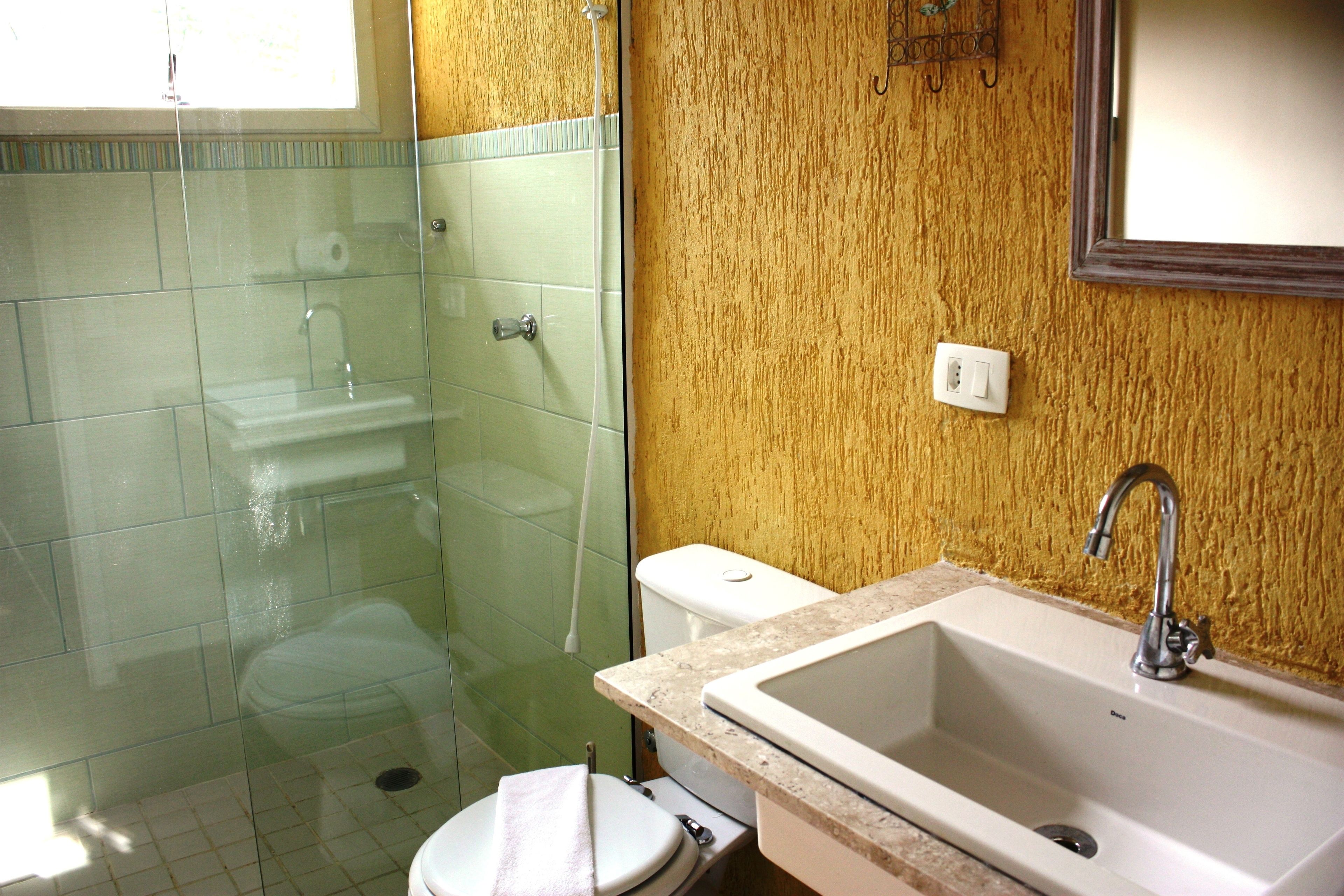 Un bagno con cabina doccia in vetro, un water e un lavabo con specchio sopra.