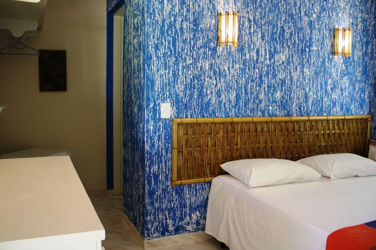 A room with a bed, a bedside table, and a wall with a textured blue pattern.