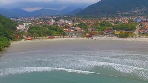 Un pueblo costero con playa, edificios y montañas al fondo.