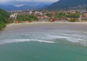 Perto da praia, guarda-sóis, prática de vôlei de praia 