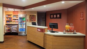 A hotel reception area with a wooden reception desk, a refrigerator stocked with beverages, and a 'hello' sign. - TownePlace Suites by Marriott Austin Round Rock (Austin)