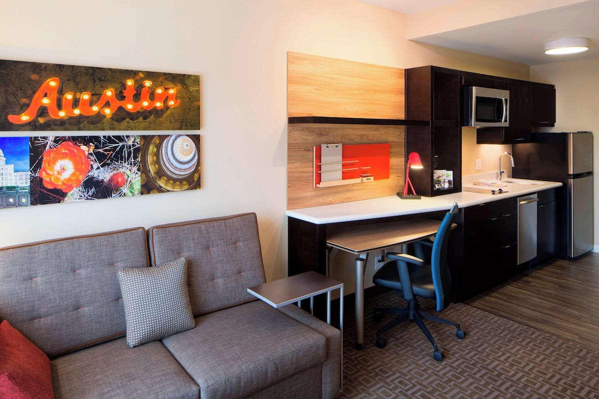 A modern apartment with a kitchenette, a sofa, and a desk.