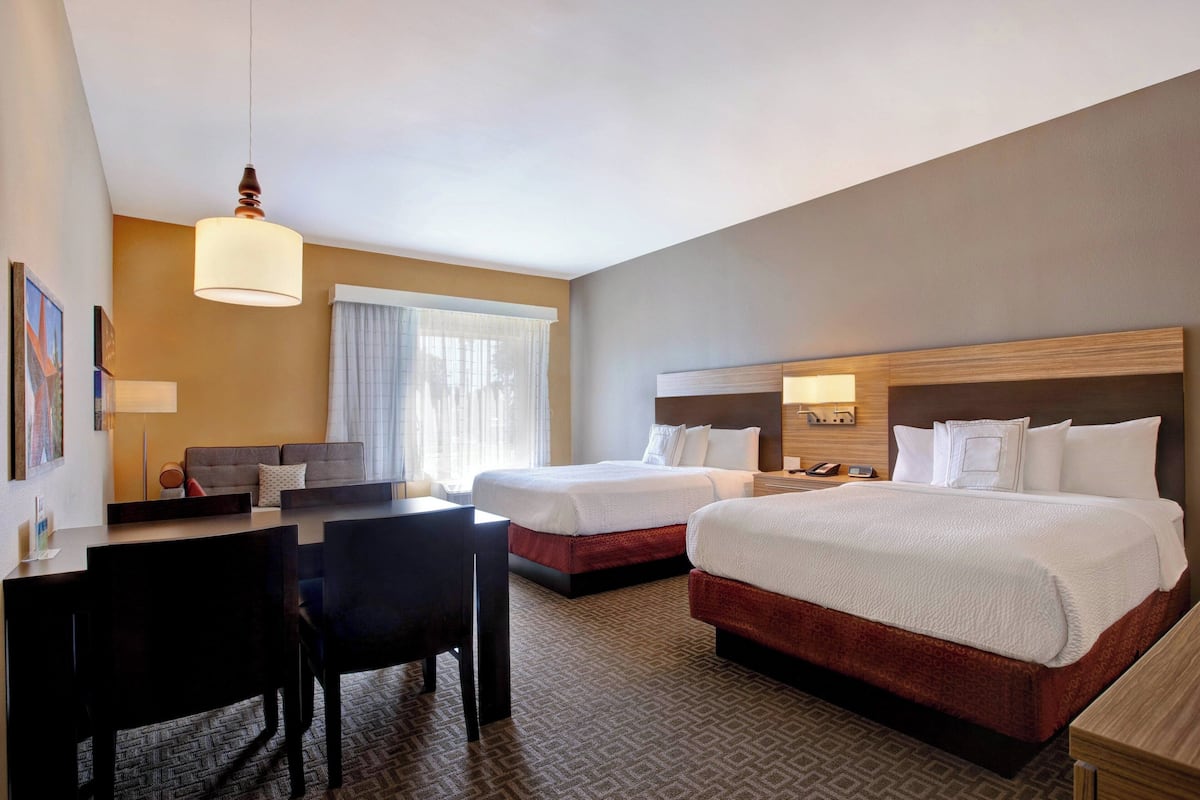 A hotel room with two beds, a desk, and a chair.
