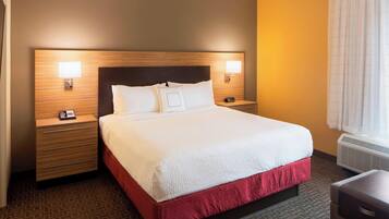 A hotel room with a large bed, two bedside tables, a nightstand, a desk, and a window with curtains.