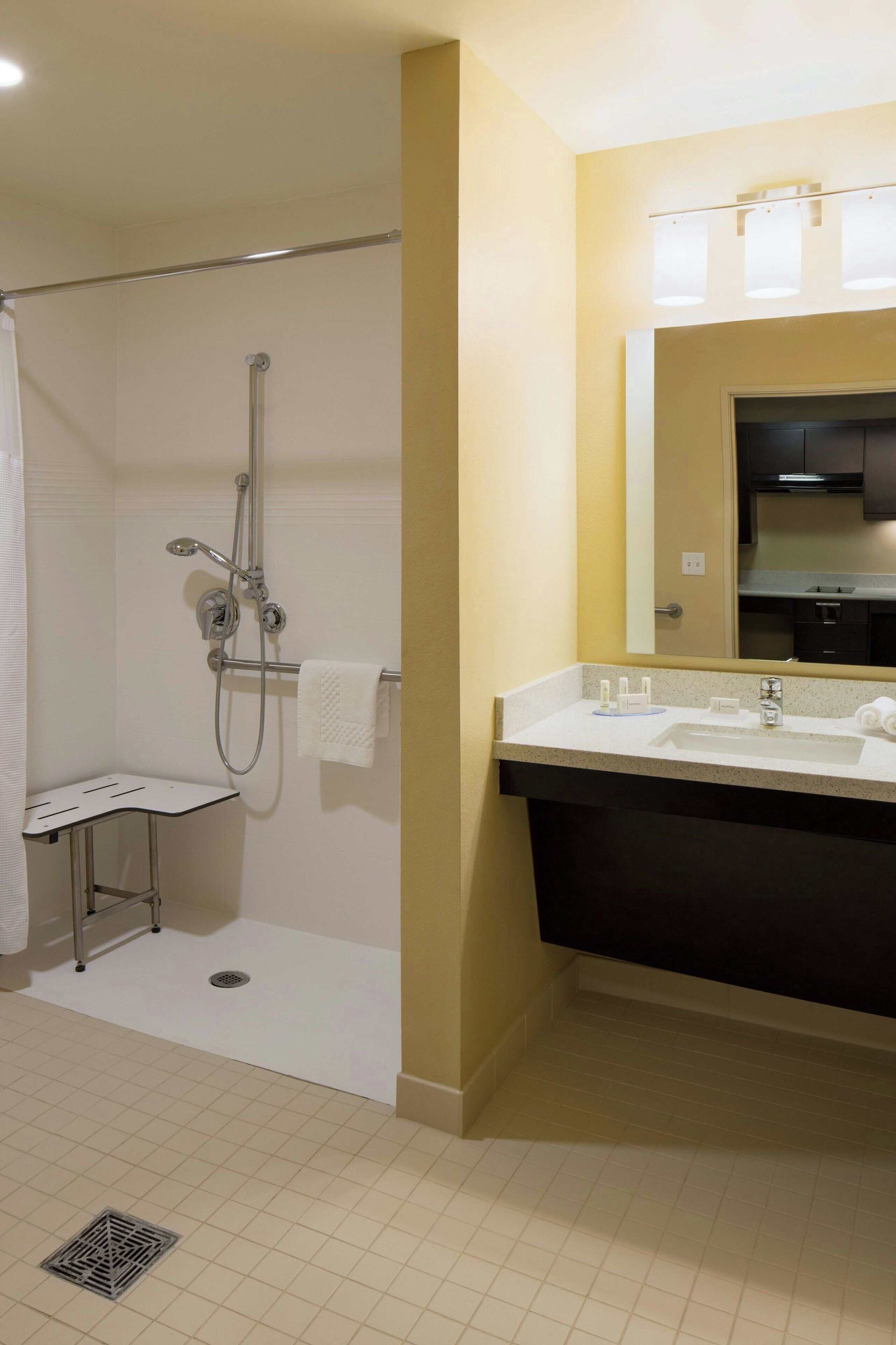 A bathroom with a shower, a sink, and a mirror.