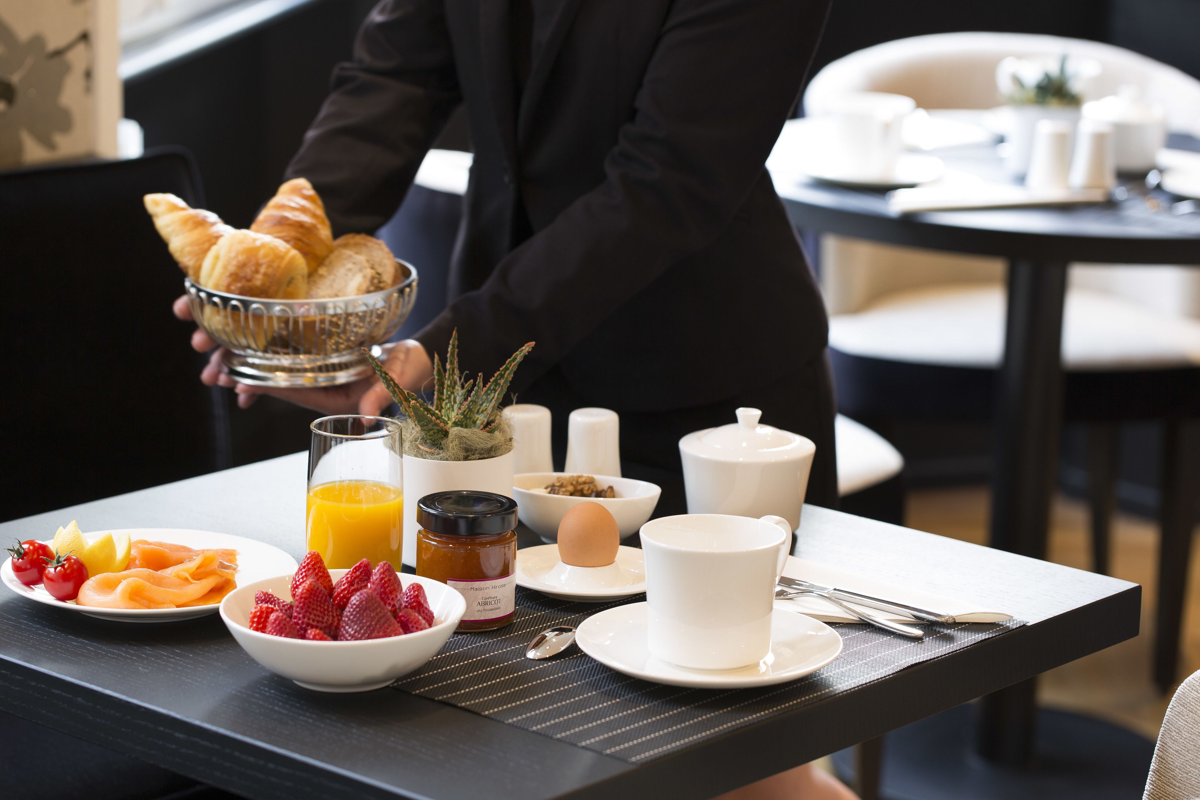 A breakfast setup with croissants, fruit, and a glass of orange juice on a table.