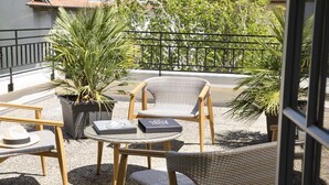 Eine Terrasse mit Korbstühlen, einem runden Tisch und einem Blumentopf.
