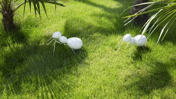 A grassy area with a palm tree and a white ant sculpture.