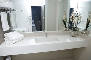A modern bathroom with a large sink, a mirror, and a towel rack.