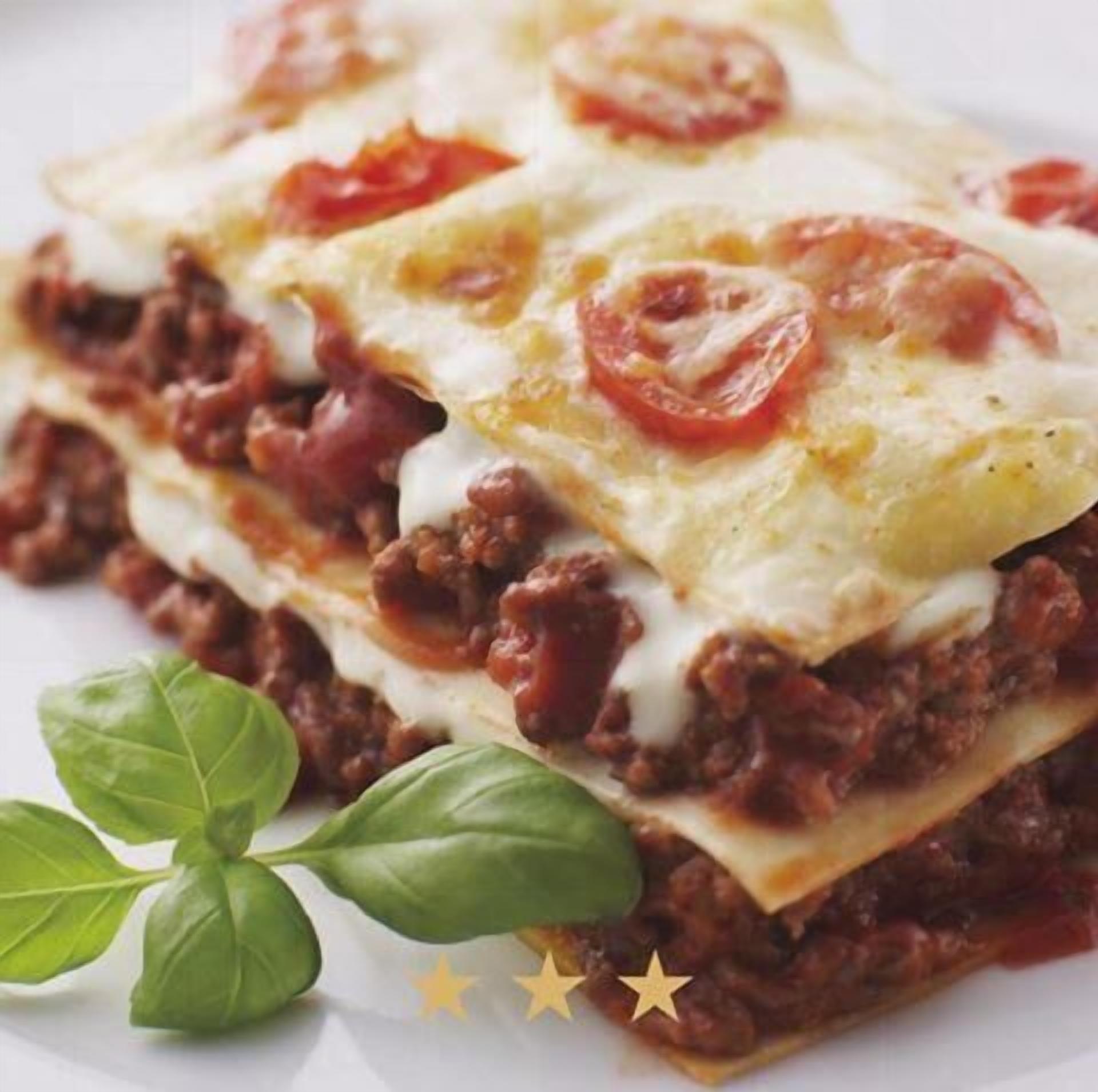 Un plato en capas con carne, queso y rodajas de tomate.