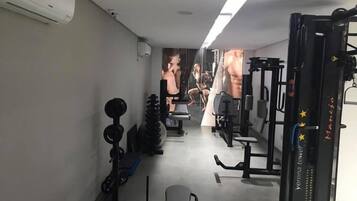 A gym with various exercise equipment, including a bench, weight racks, and a squat rack.