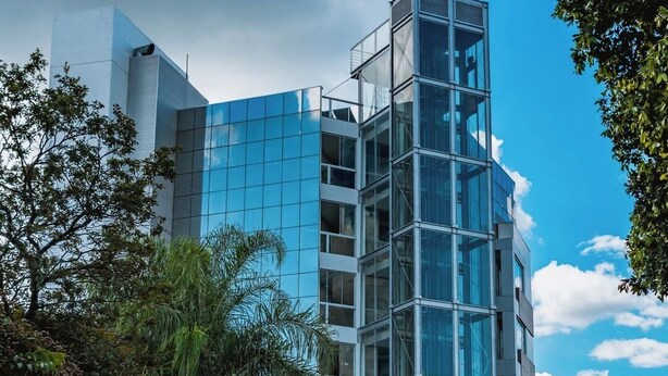 Un hotel moderno con fachada de vidrio, un letrero llamativo que dice "HOTEL verona tower" y vistas del área urbana circundante.