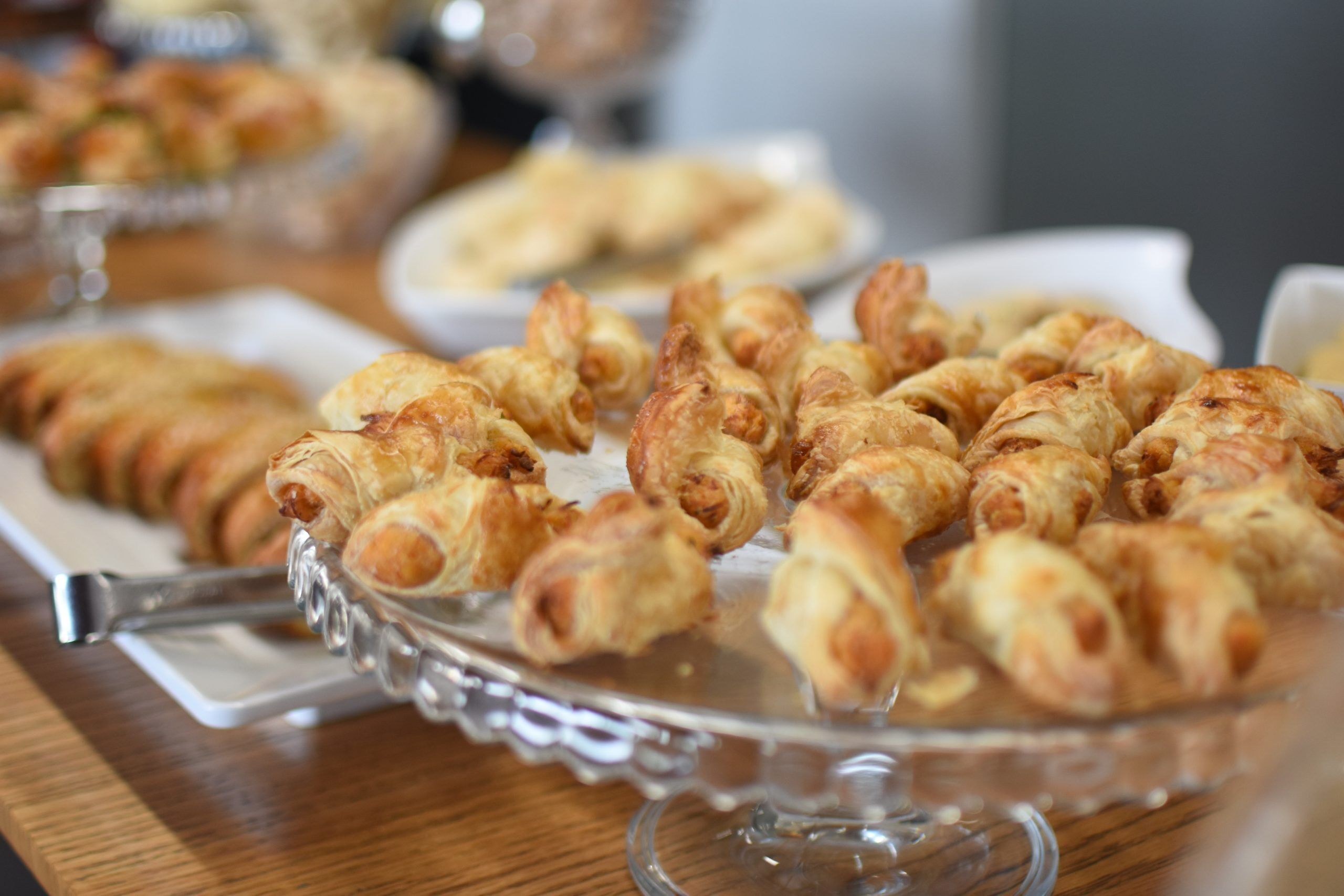 Et glassfad fyldt med croissanter på et træbord.
