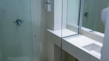 Un baño moderno con ducha envuelta en vidrio, un lavamanos blanco y un inodoro con una toalla.