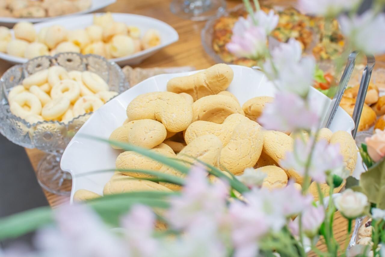 Una mesa de buffet con diversos alimentos, incluyendo un plato de galletas amarillas y un tazón de galletas con forma de anillo.