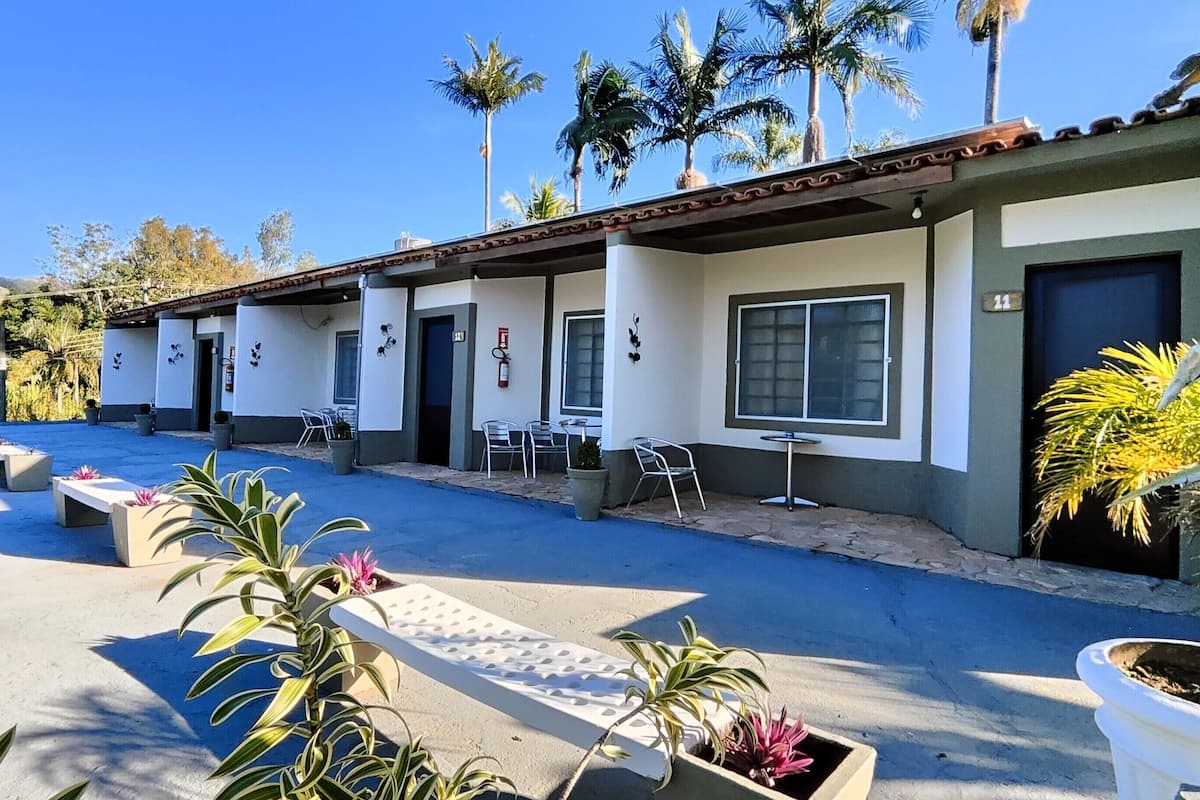 A motel with outdoor seating, potted plants, and palm trees in the background.