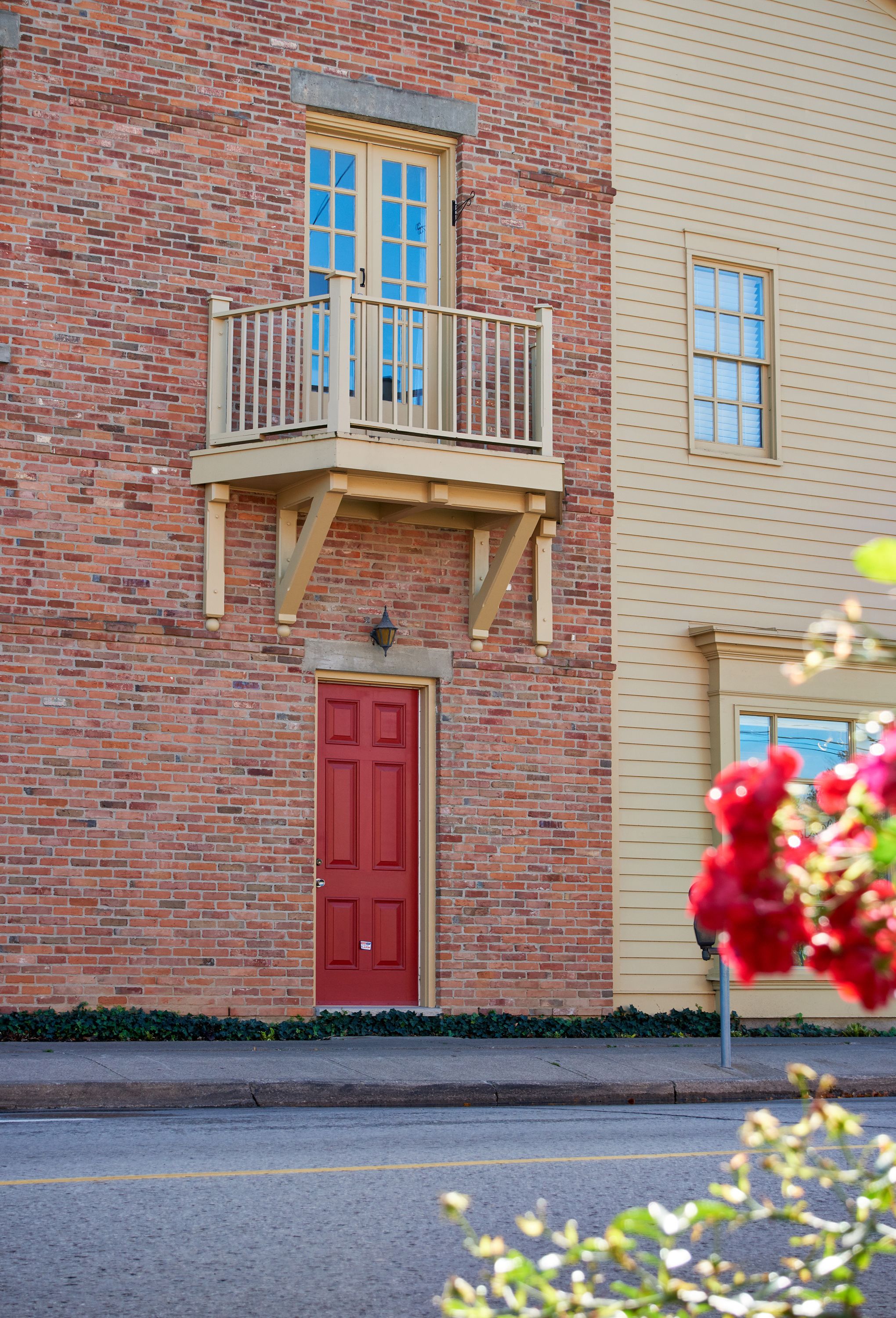 A two-story building with a red door and a balcony.