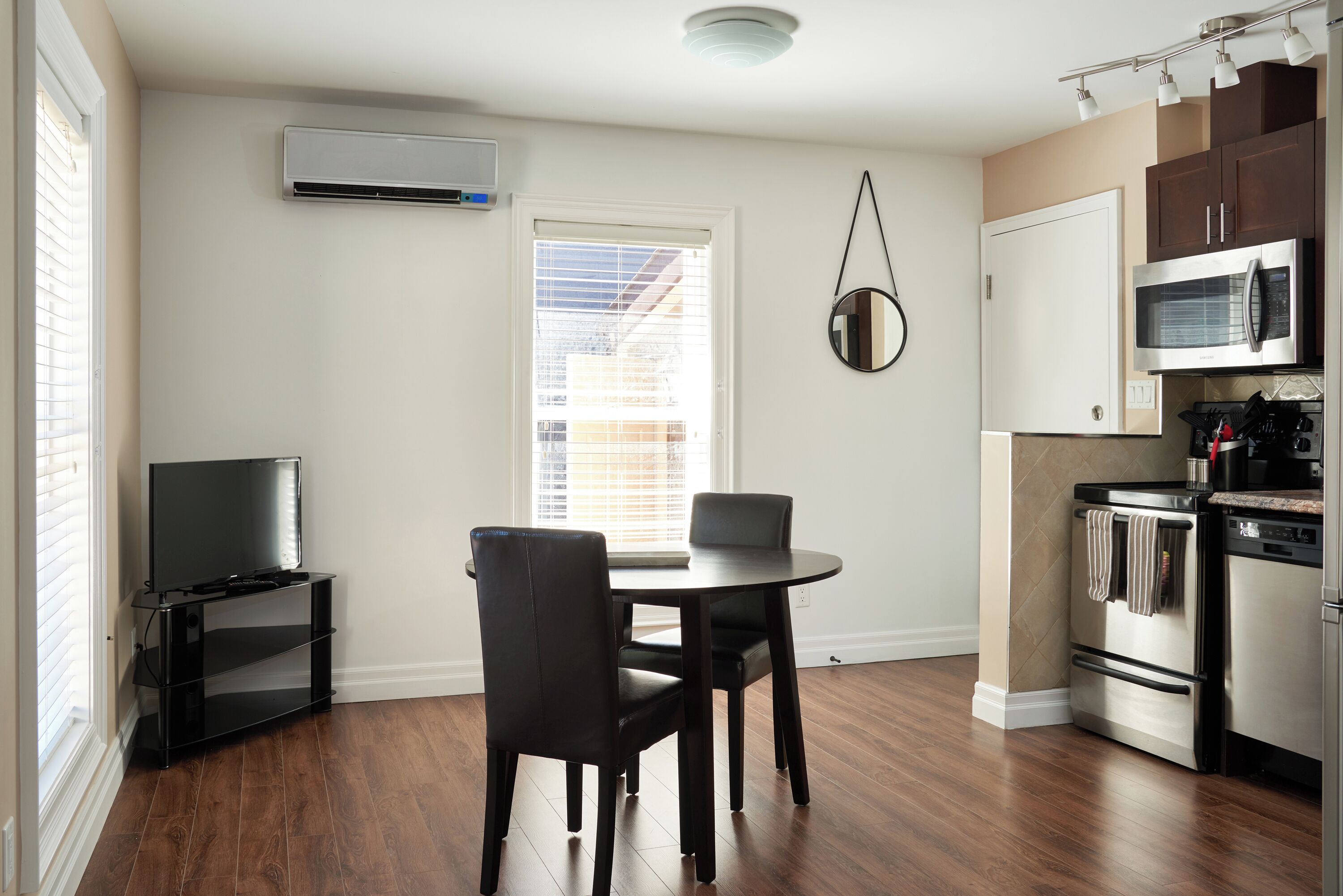 A modern kitchen with a dining area, built-in appliances, and a TV.