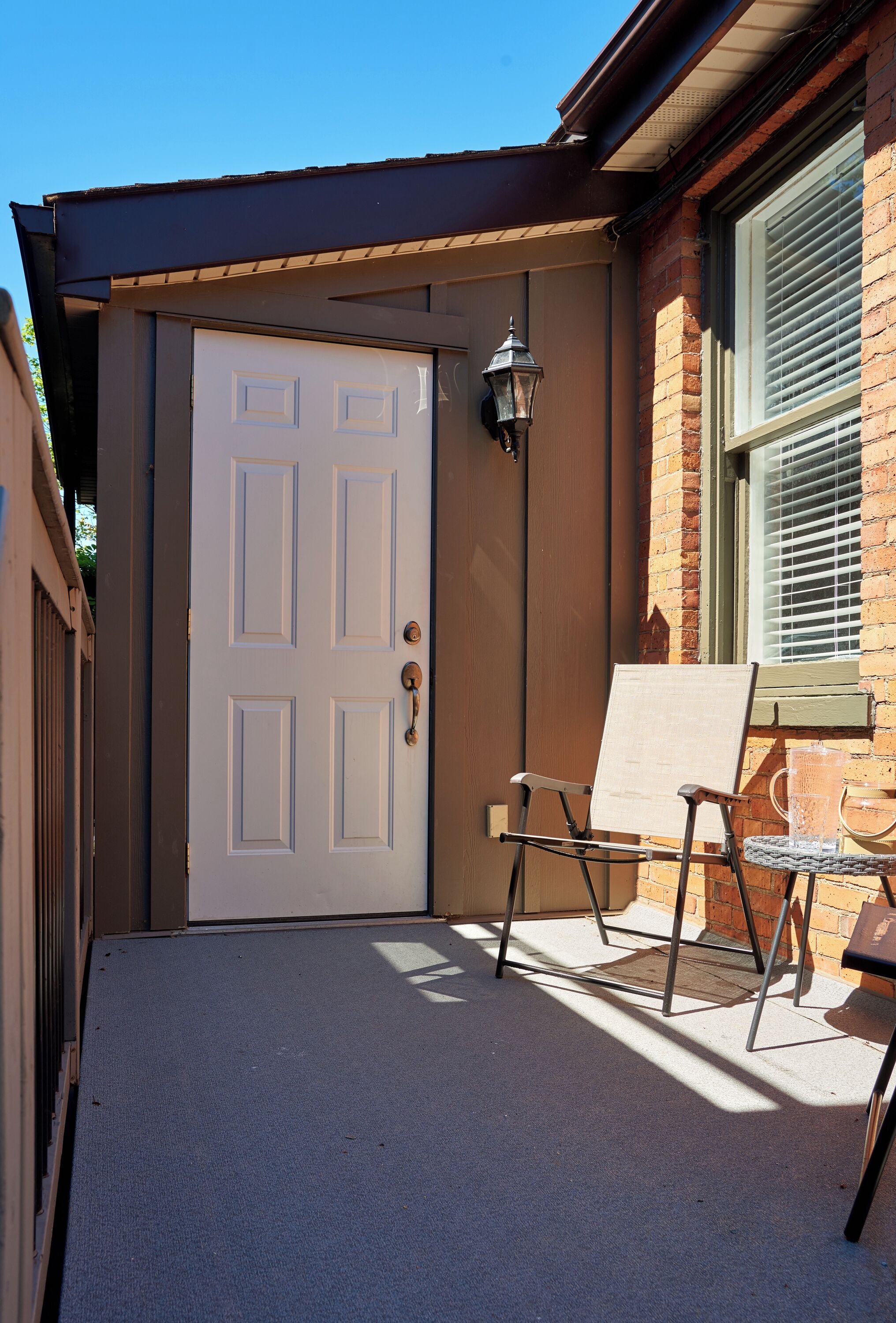 A white door with a metal handle, a metal lantern, and a metal chair with a metal frame.