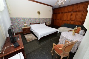 Quarto com cama, escrivaninha com computador, cadeira, mesinha de cabeceira com abajur e guarda-roupa.