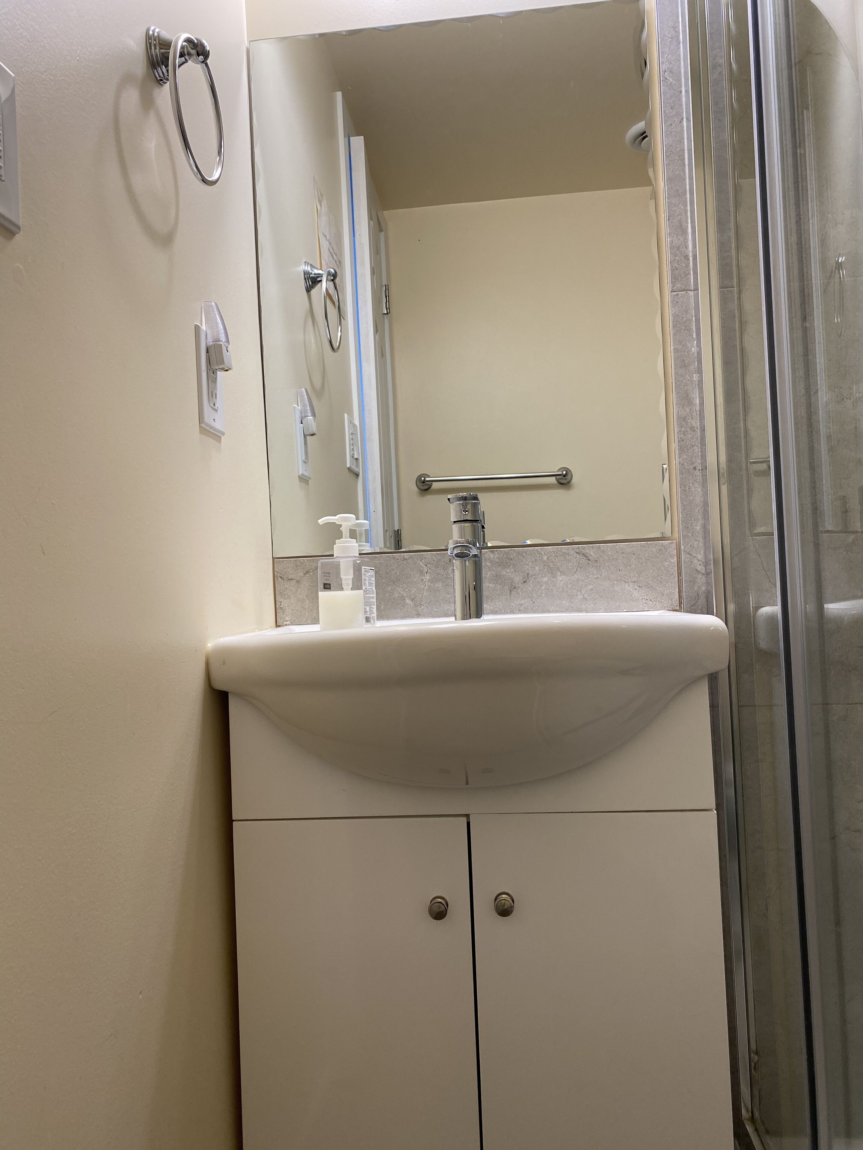 Un baño con lavamanos, espejo y ducha.
