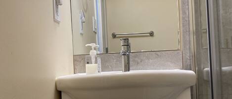 Un baño con lavamanos, espejo y ducha.
