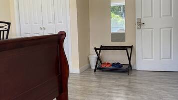 A room with a pool table, a door with a keypad lock, a trash bin, and a shoe rack with slippers.