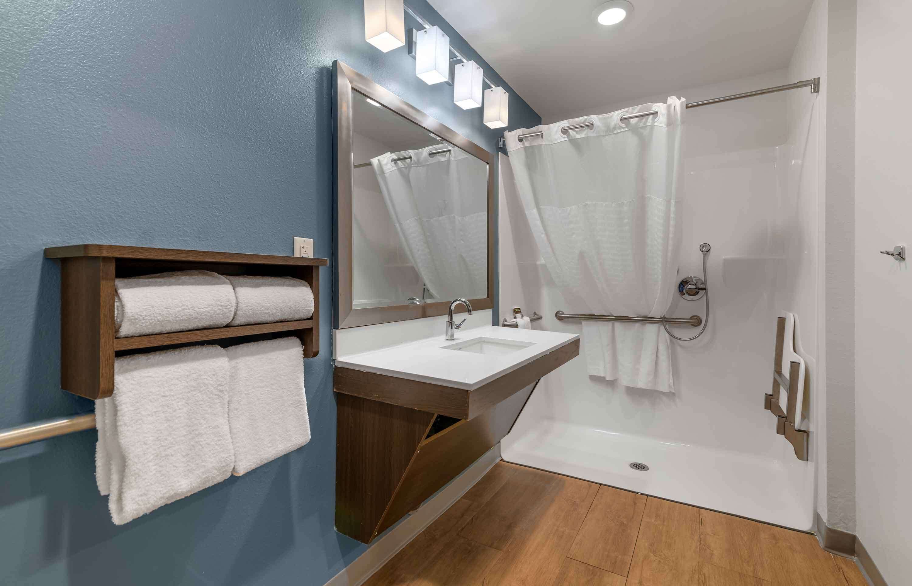 Een badkamer met een wastafel, spiegel en douche.