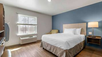 A bedroom with a bed, a window with blinds, a bedside lamp, and a heater.