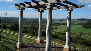 A pergola with white columns and a wooden deck overlooking a green landscape. - Hotel Mosteiro Brotas (Brotas)