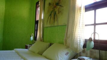 Quarto com cama, almofadas, abajur e um quadro na parede.