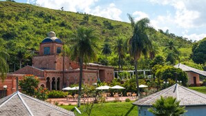 A building with a dome and arched windows, surrounded by a garden with palm trees and outdoor seating. - Hotel Mosteiro Brotas (Brotas)