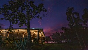 Un bâtiment moderne doté de grandes fenêtres en verre et où l’on peut voir la lune dans le ciel.
