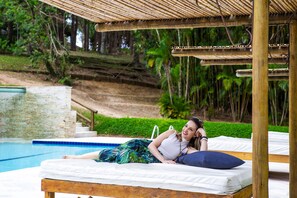A wooden deck with a pool and a stone wall. - Itu Garden Spa (Itu)