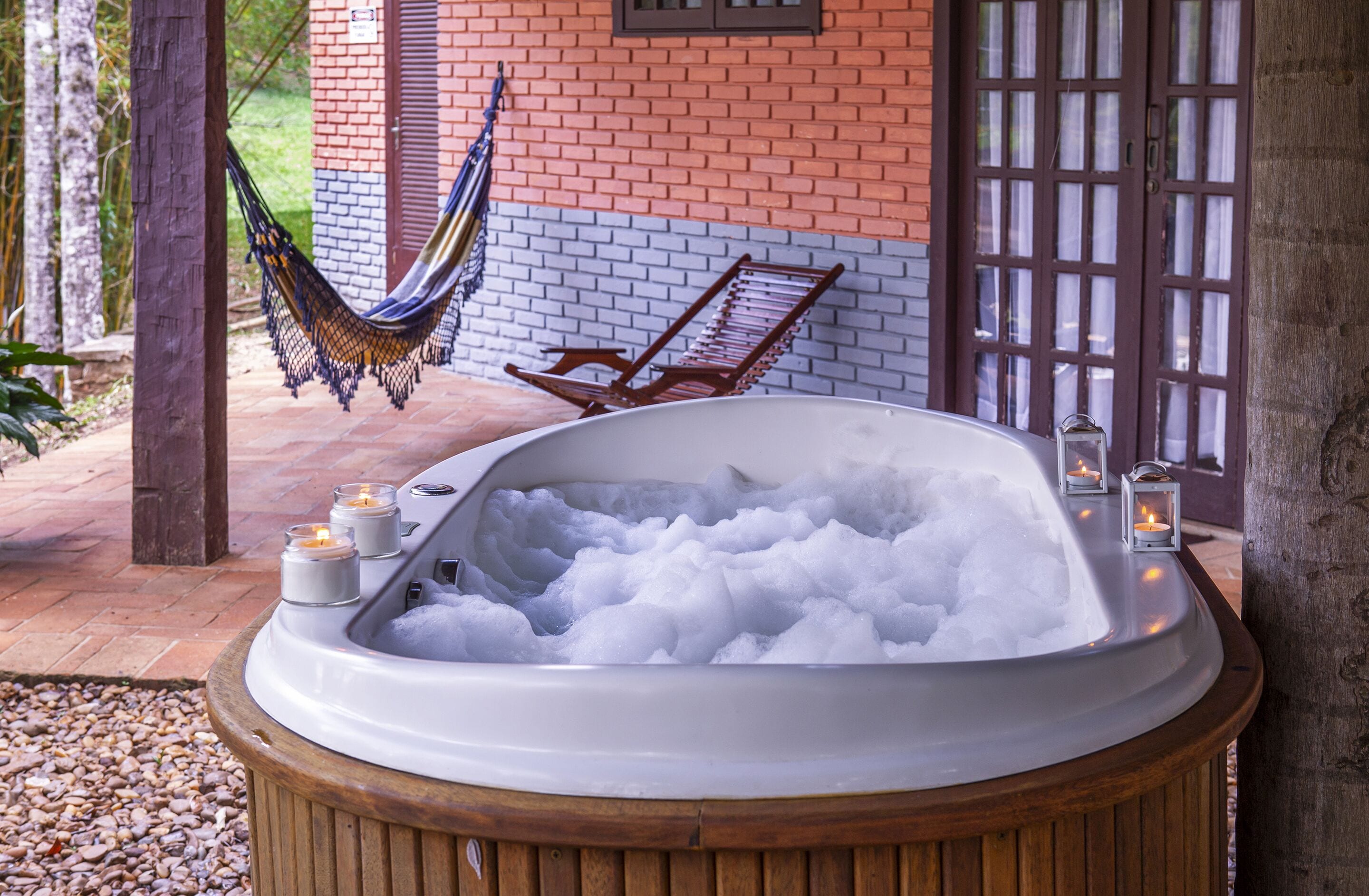 Un jacuzzi lleno de hielo, rodeado por una terraza de madera, con una hamaca y un banco al fondo.