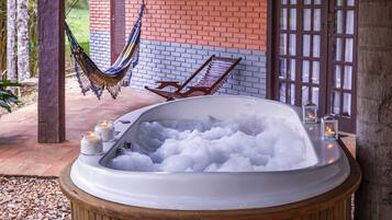 Un jacuzzi lleno de hielo, rodeado por una terraza de madera, con una hamaca y un banco al fondo.