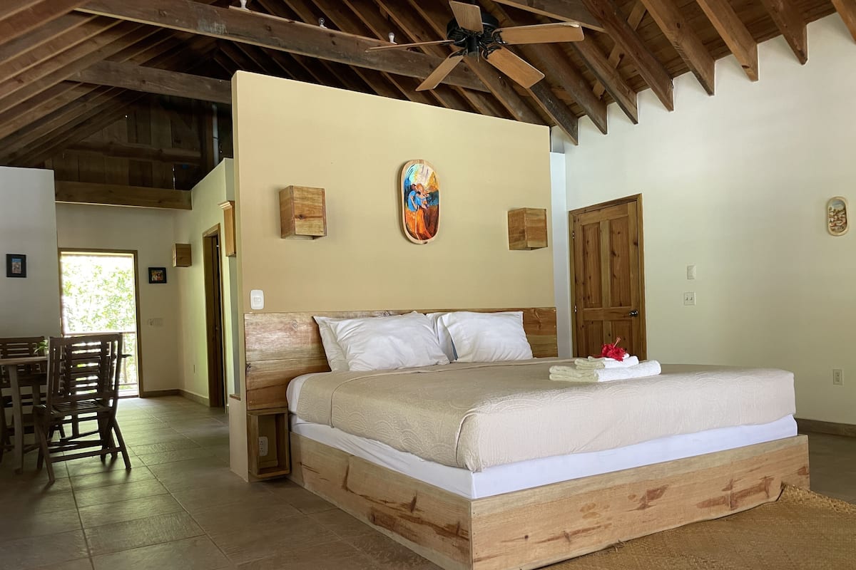 A bedroom with a wooden bed, a ceiling fan, and a door leading to another room.