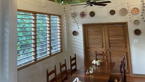 A dining area with a long wooden table, chairs, and a ceiling fan. - Hotel Guanaja (Guanaja)