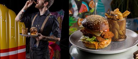 A person holding a tray with a burger and fries, and a colorful background with various patterns.