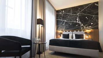 Una habitación de hotel moderna con una cama grande, un escritorio, una silla y un mural con un mapa en la pared.