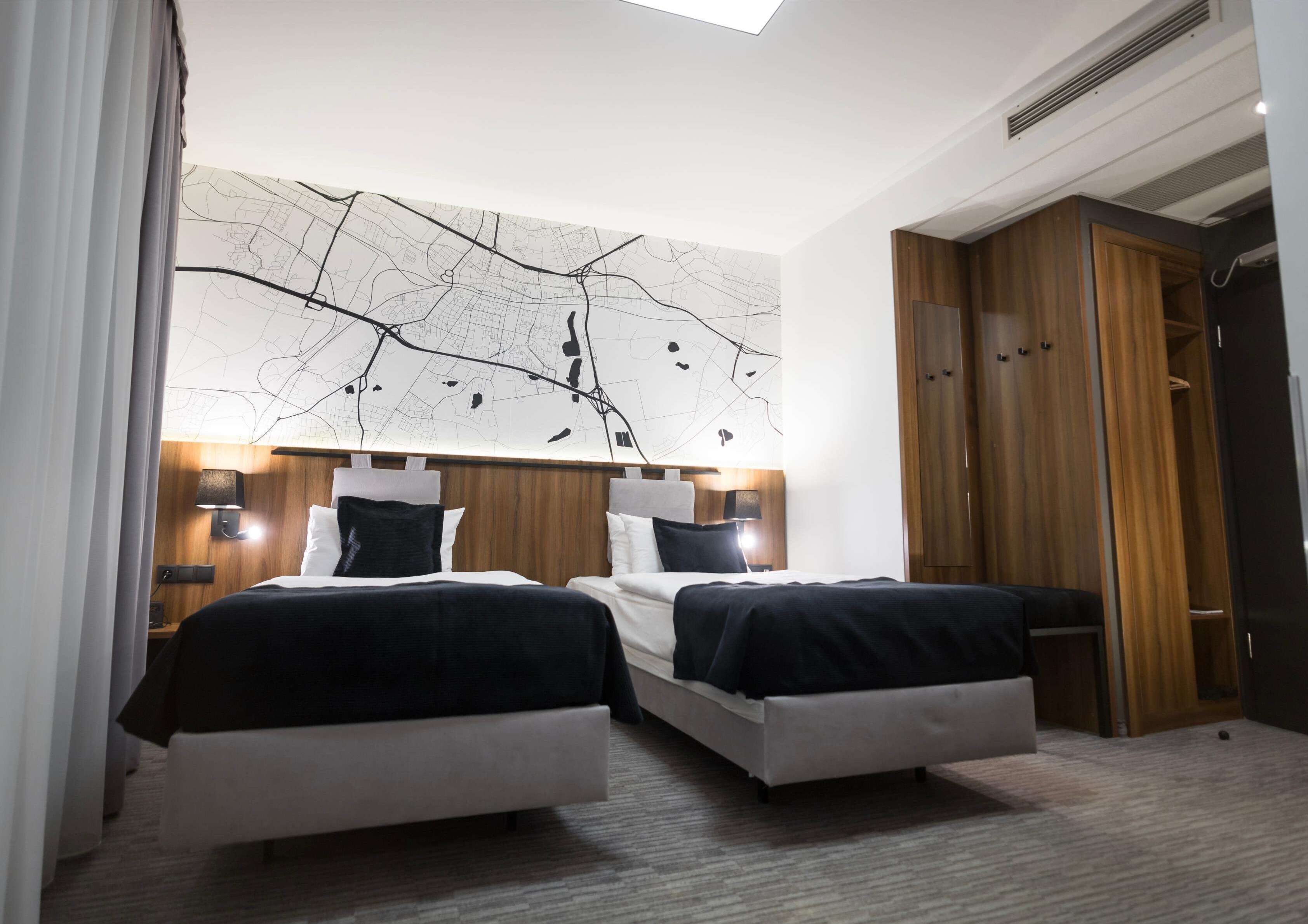 Une chambre d’hôtel avec deux lits, une grande carte murale et une armoire.