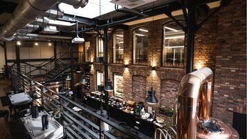 A restaurant with exposed brick walls, hanging industrial-style lights, and a visible kitchen area with copper equipment.