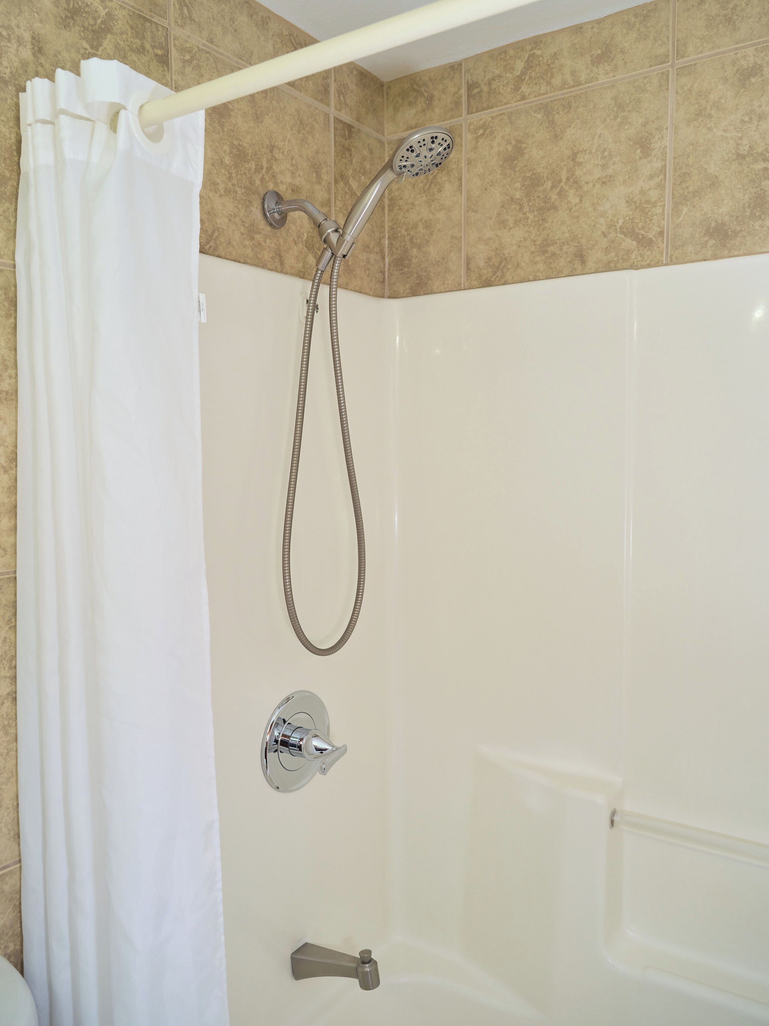 A shower with a handheld showerhead and a wall-mounted faucet.