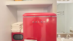 A red Galanz refrigerator in a bathroom with a sink and mirror. - The Oakwood Inn (Sterling)