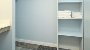 A walk-in closet with light blue walls, wooden shelves, and a white countertop. - The Oakwood Inn (Sterling)