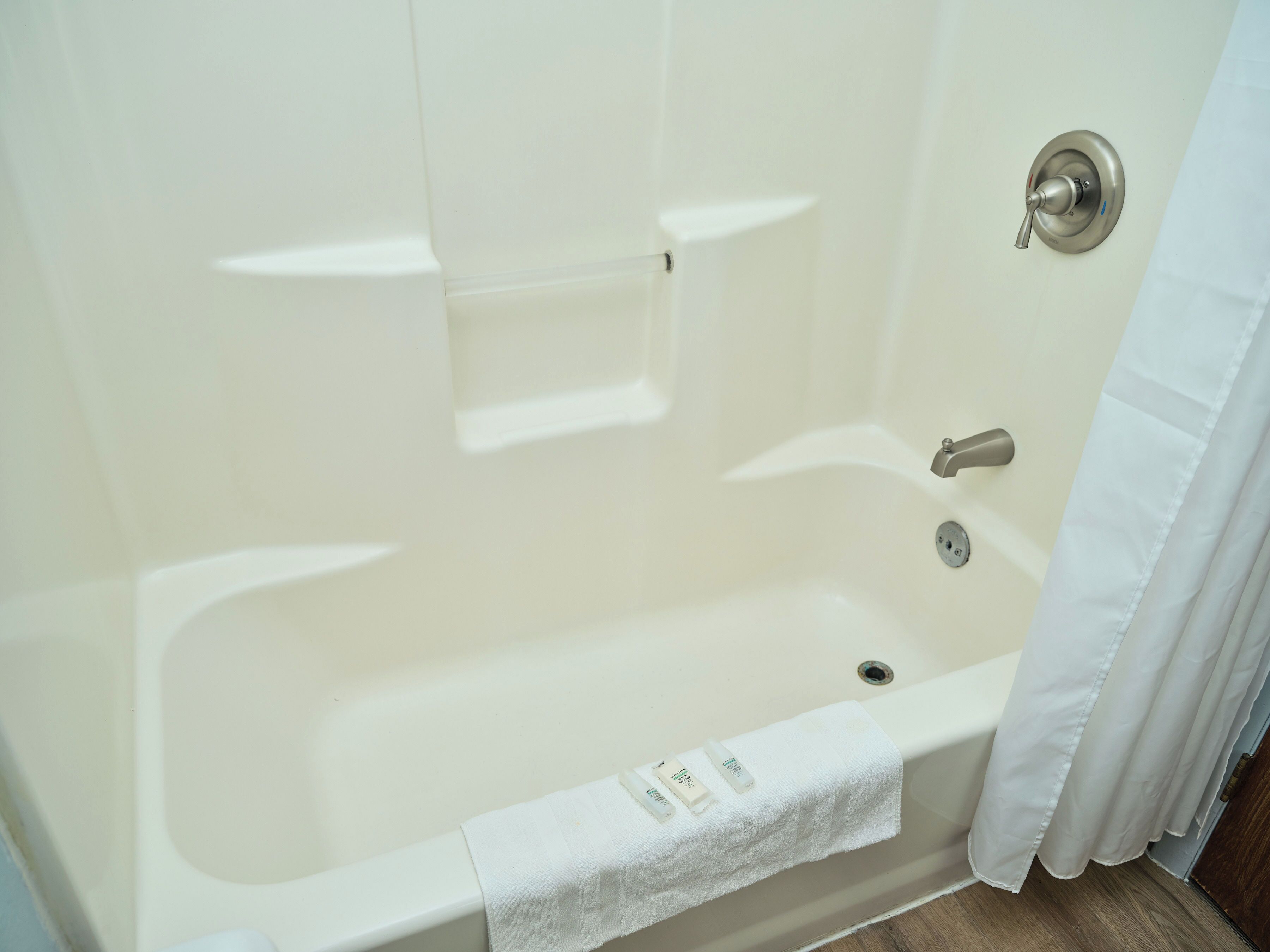 Une baignoire blanche avec un rideau de douche, une serviette et un robinet.