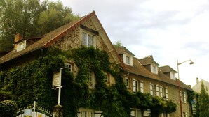 Ein aus Stein gebautes Gebäude, das von Efeu überwuchert ist, mit einem ehrwürdigen Eingangstor und Schildern, die es als Hotel kennzeichnen.