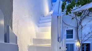 A white spiral staircase leading to a door with a potted plant beside it.