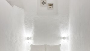 A minimalist bedroom with a bed, two bedside tables, and a wall-mounted light fixture.